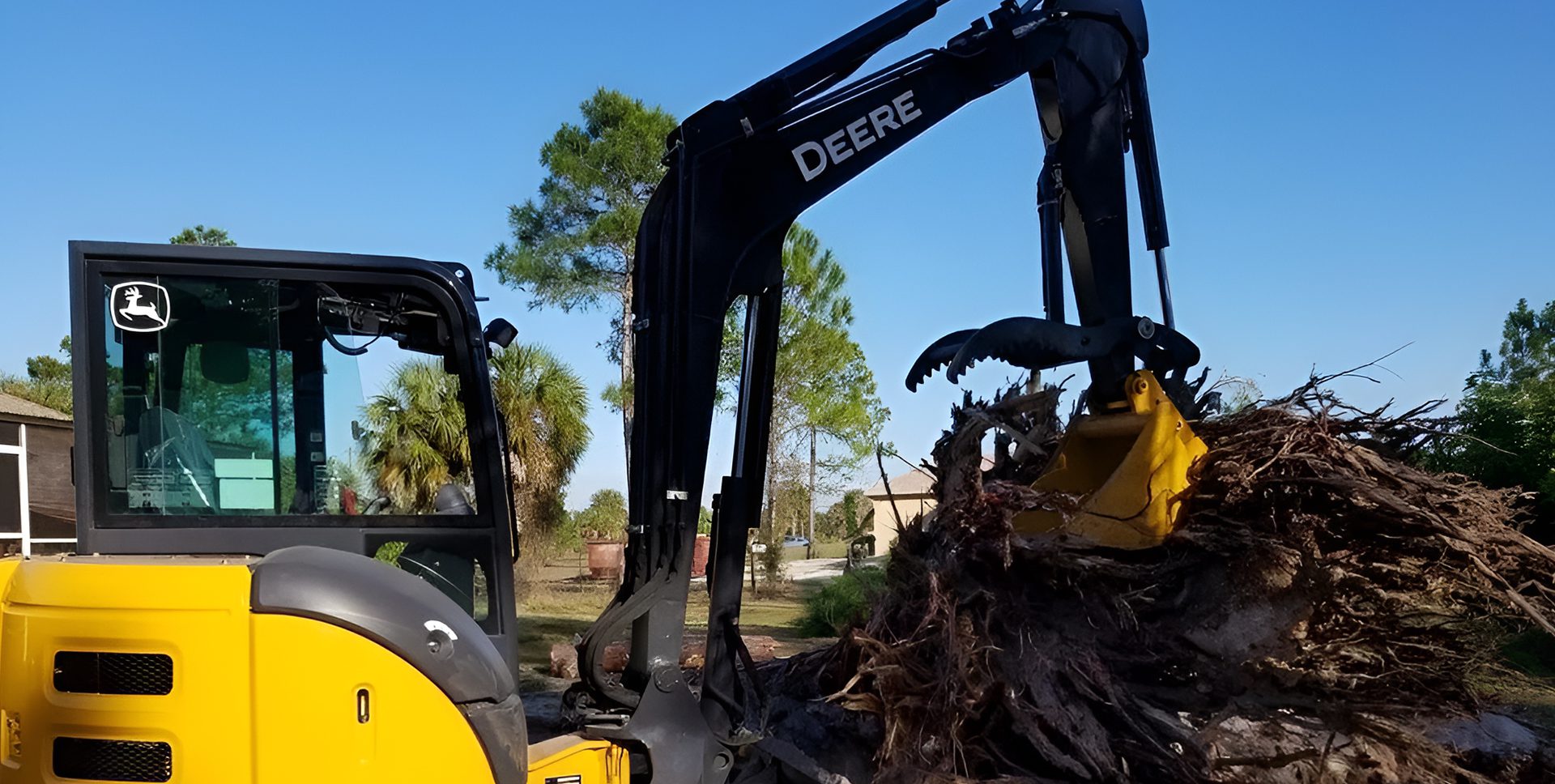 John Deere excavator removing tree roots.
